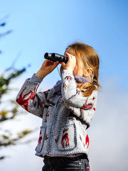 Linda niña investigando montañas de los Alpes usando binocular. T — Foto de Stock