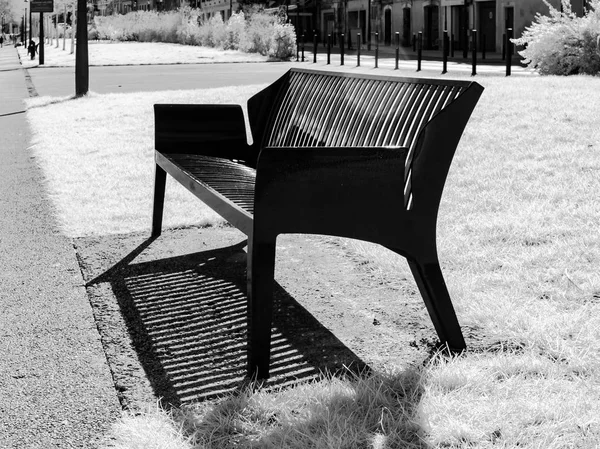 Nové kovové lavička na jasného slunečního světla ve veřejném parku podél řeky — Stock fotografie