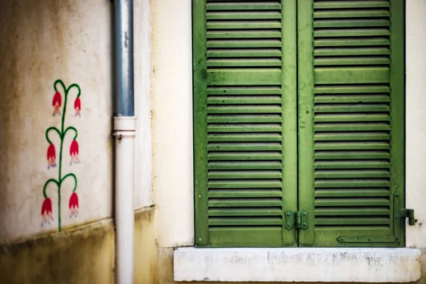 Closed window with green shutters and painted wall of old house — Stock Photo, Image