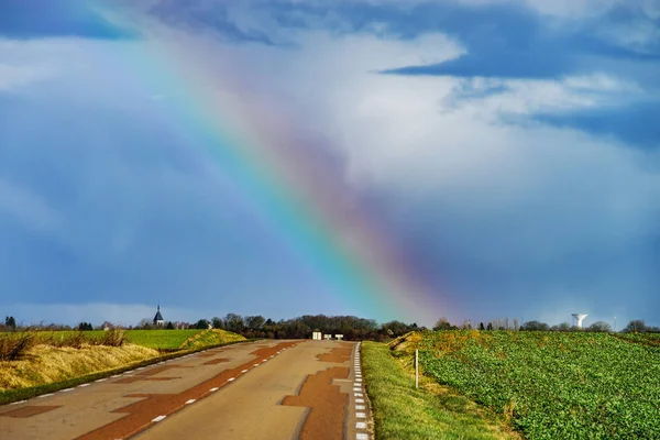 Vacker färgglad regnbåge i slutet av asfalterad väg, perspecti — Stockfoto