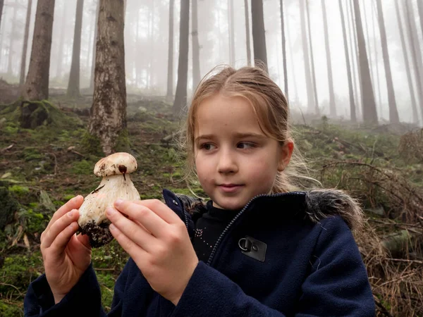 Klein meisje demonstreert een witte paddestoel die net op de voorgrond is gevonden — Stockfoto