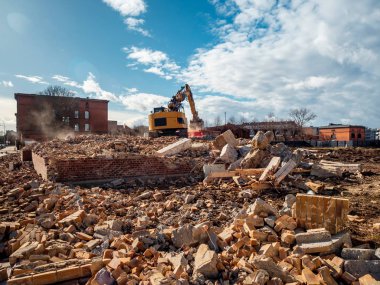 An excavator breaks down an old building. Dust, bricks and broke