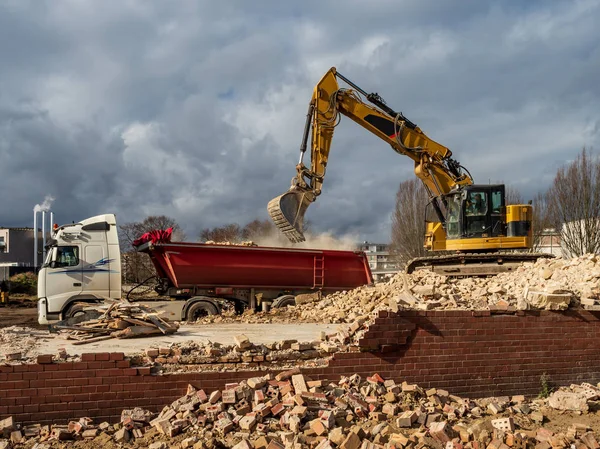 Un escavatore demolisce un vecchio edificio. Polveri, mattoni e rotture — Foto Stock