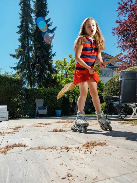 Een Schoolmeisje Poseert Met Een Bezem Tuin Terwijl Rolschaatst Huishoudster — Stockfoto