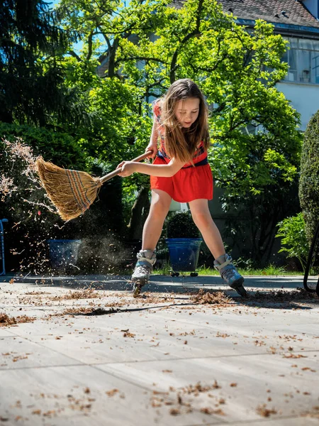 一个女学生在院子里摆着扫帚 一边打滚一边摆姿势 在花园里打扫卫生清洁自动化 并将其转化为娱乐 阳光灿烂的天气快乐的童年 — 图库照片
