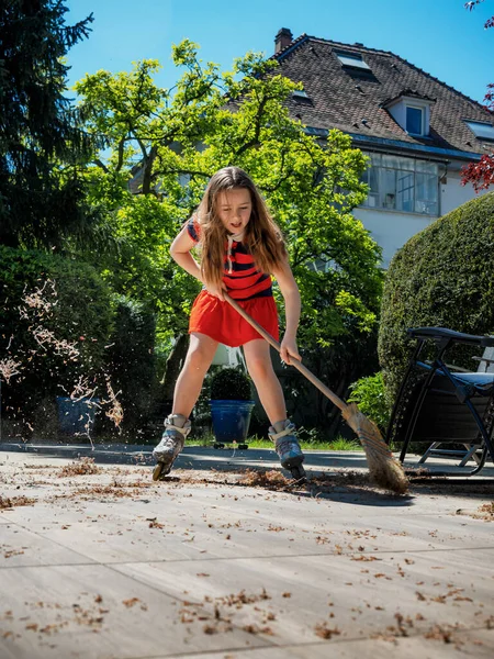 Een Schoolmeisje Poseert Met Een Bezem Tuin Terwijl Rolschaatst Huishoudster — Stockfoto