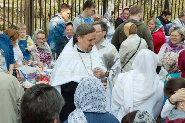 Moskova, Rusya - 27 Nisan 2019: Ortodoks bir rahip Hıristiyanlara kutsal su serpiyor ve geleneksel suyu aydınlatıyor. Moskova 'da büyük dini bayram.