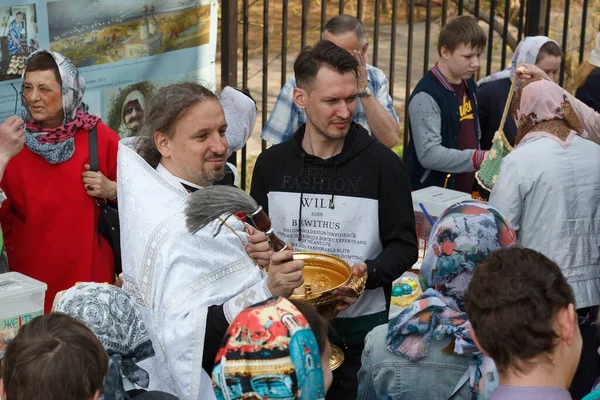 Moskova, Rusya - 27 Nisan 2019: Ortodoks bir rahip Hıristiyanlara kutsal su serpiyor ve geleneksel suyu aydınlatıyor. Açık havada..