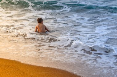 Küçük çocuk deniz kenarında yüzmeyi öğreniyor. Aktif yaşam tarzı. Hafta sonları, tatiller. Fotoğraftaki güneş ışığı.