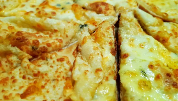 Pişmiş iştah açıcı dört dilim pizza ince hamur üzerinde Rokfor peyniri, parmesan peyniri rendelenmiş, peynir rendelenmiş, mozarella masada uzanıyor ve yakın çekim gösteriliyor.