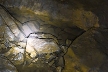 Mağaradaki suda yatan taş, parlak ışıkla aydınlatılıyor. Altın ışınlar bir kaldırım taşının üzerine düşüyor. Arkeoloji, Jeoloji, Mineraller.