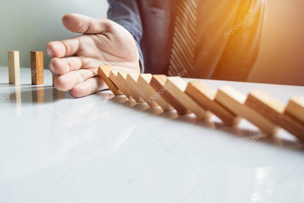 businessman hand stop dominoes