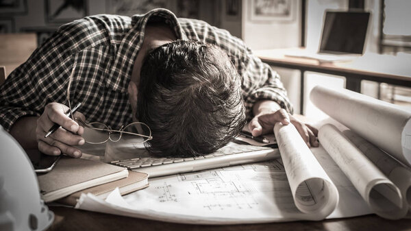 tired engineer lying on blueprint