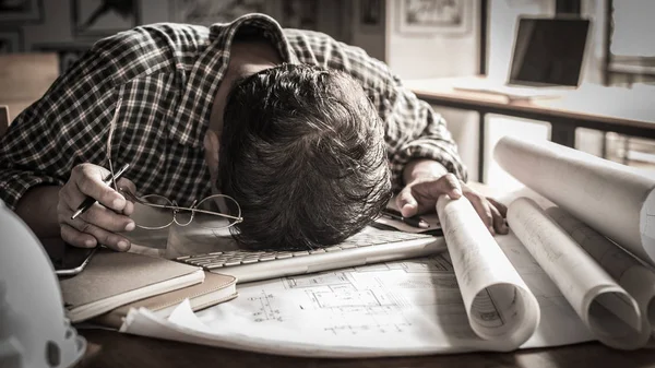 Tired engineer lying and sleeping on blueprint with dark retro s — Stock Photo, Image