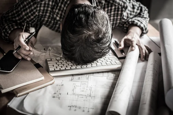 Tired engineer lying and sleeping on blueprint with dark retro s — Stock Photo, Image