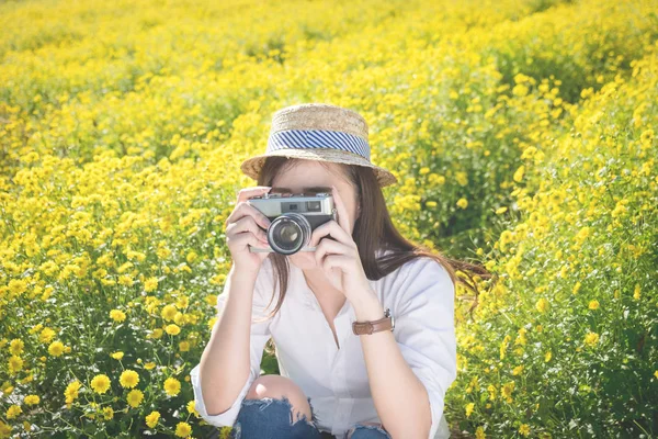 카메라와 함께 노란 꽃밭에 아시아 hipster 귀여운 십 대 소녀 — 스톡 사진