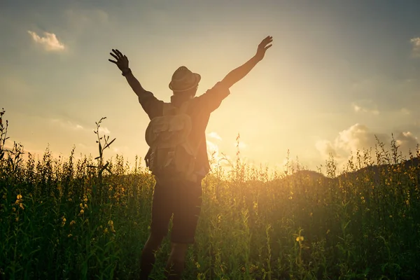 Silhouette eines Mannes, der seine Arme am Abendhimmel und im Garten erhebt — Stockfoto