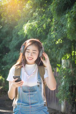 Genç Asyalı hipster giymek sm üzerinden müzik kulaklık