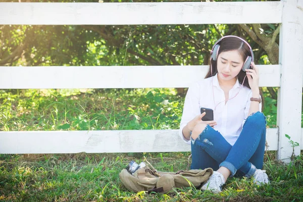 Unga asiatiska hipster bära hörlurar Lyssna på musik via sm — Stockfoto