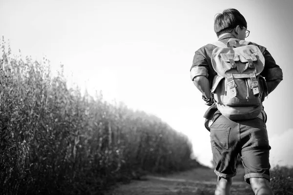 Молодий чоловік Мандрівник з рюкзаком, що розслабляється на відкритому повітрі зі скелястими мухами — стокове фото