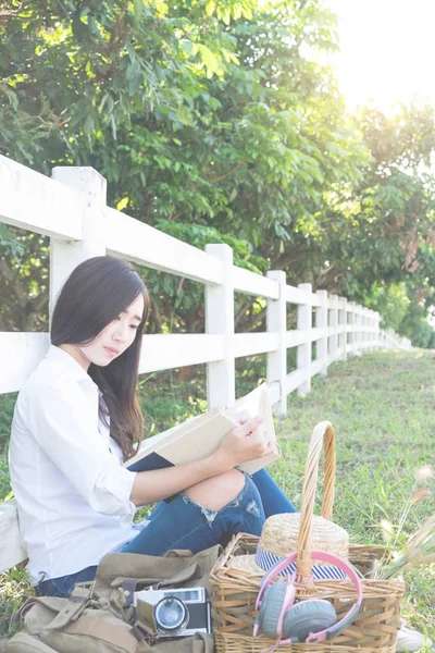 잔디가 르에서 책을 읽고 꽤 편안한 젊은 아시아 여자 — 스톡 사진
