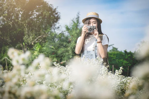 Asiático hipster lindo adolescente chica con cámara en blanco flor jardín , — Foto de Stock