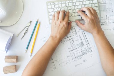Architect or engineer working on keyboard blueprint and architec clipart