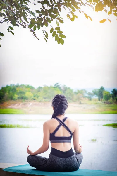 Vista posteriore primo piano della donna eseguire meditando yoga sul natur — Foto Stock