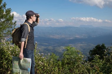 Harita sırt çantası ile kayalık açık rahatlatıcı ile genç adam Traveler
