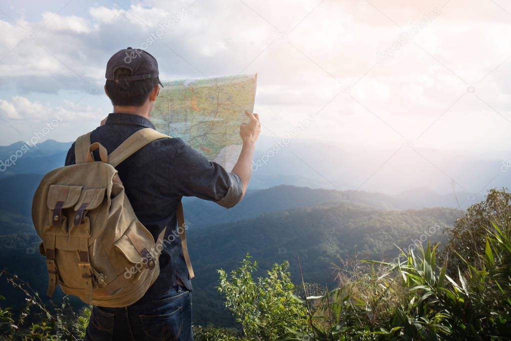 Young Man Traveler with map backpack relaxing outdoor with rocky