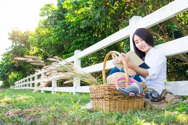 Pretty relaxed young asian woman reading a book at the lawn gare — Stock Photo, Image