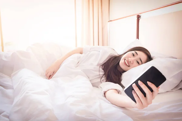 Avslappnad kvinna hemma läsa ett textmeddelande på smartphone i han — Stockfoto