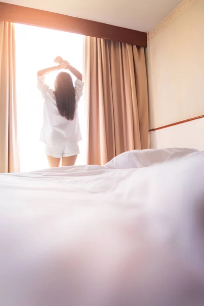 Gezonde vrouw die zich uitstrekt in bed kamer en open de gordijnen na — Stockfoto