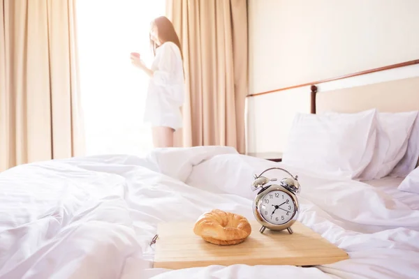 Woman stretched in bed room after the alarm clock and bread in t — Stock Photo, Image