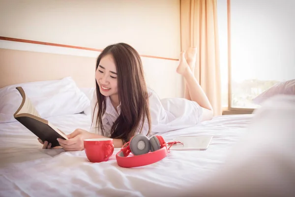 Γυναίκα διαβάζοντας το βιβλίο και να πίνει καφέ στο κρεβάτι κατά τη διάρκεια του πρωινού — Φωτογραφία Αρχείου