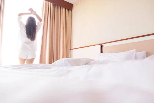 Gezonde vrouw die zich uitstrekt in bed kamer en open de gordijnen na — Stockfoto