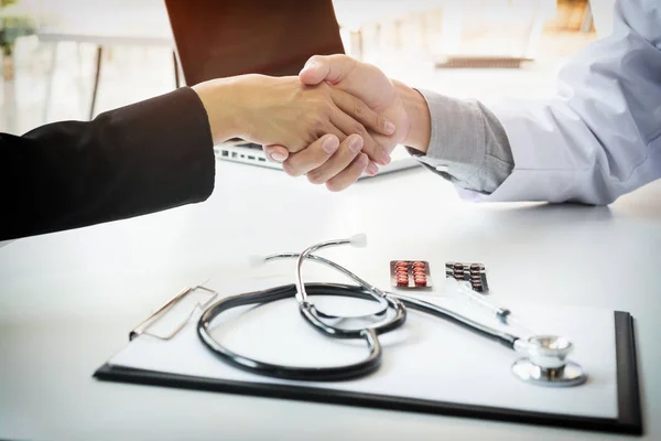 Male doctor in white coat shaking hand to female colleague — Stock Photo, Image
