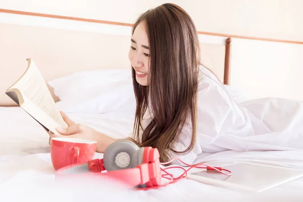 Kvinna läsa bok och dricka kaffe på sängen under Godmorgon — Stockfoto