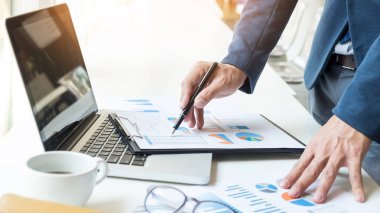 Dizüstü bilgisayar, tablet ve grafik dat ile ofisinde çalışan iş adamı