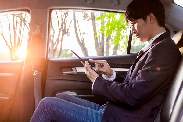 Young handsome businessman working in back of car and using a ta — Stock Photo, Image