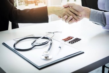 Kadın meslektaşım için el sallayarak beyaz montlu erkek doktor 