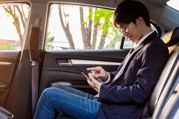 young handsome businessman working in back of car and using a ta