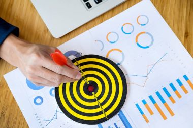 Business Man hand holding a target with darts hitting the center clipart
