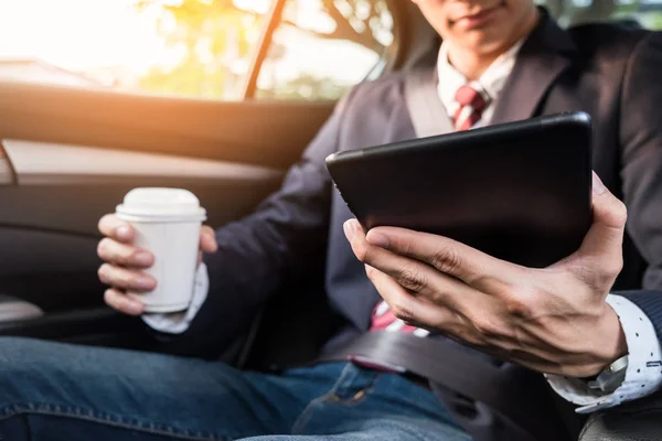 young handsome businessman working in back of car and using a ta