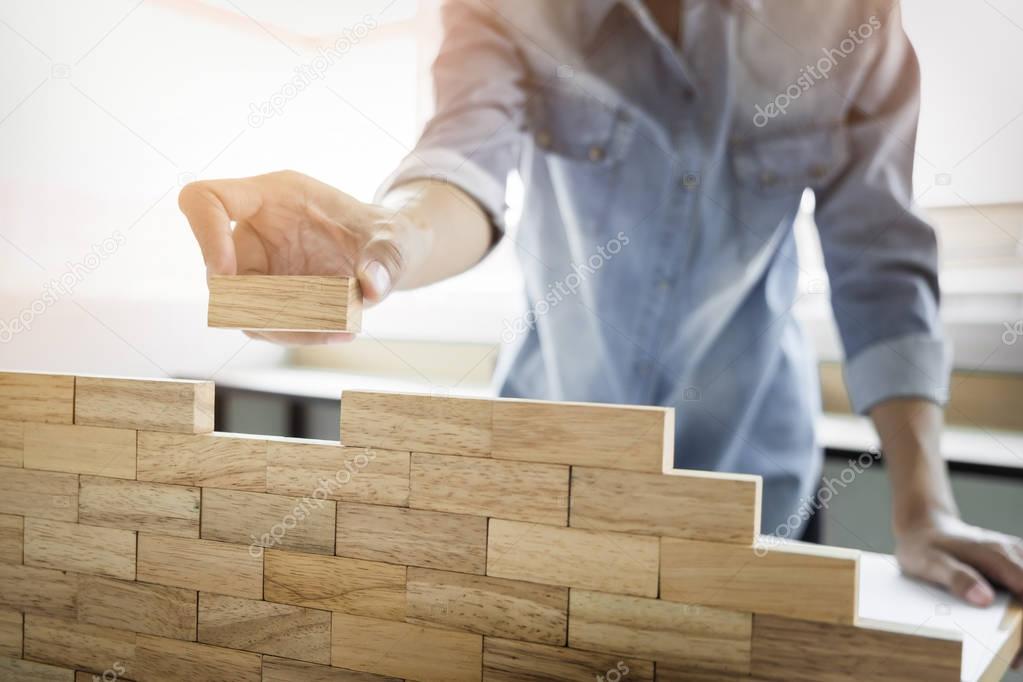 Hand of engineer playing a blocks wood tower game (jenga) on blu