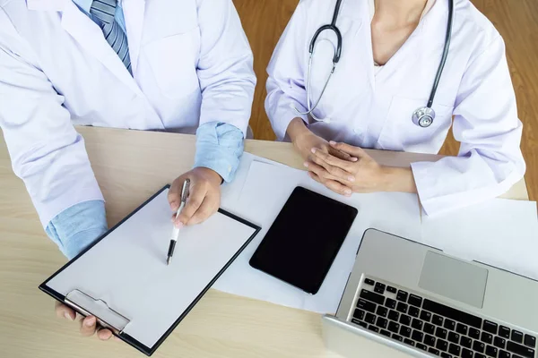 Two doctors discussing patient notes in an office pointing to a — Stock Photo, Image