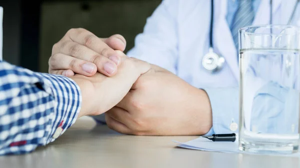 Male doctor holding patient's hand, comforting patient who is in — Stock Photo, Image