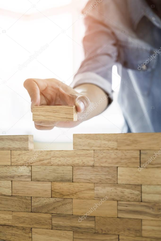 Hand of engineer playing a blocks wood tower game (jenga) on blu