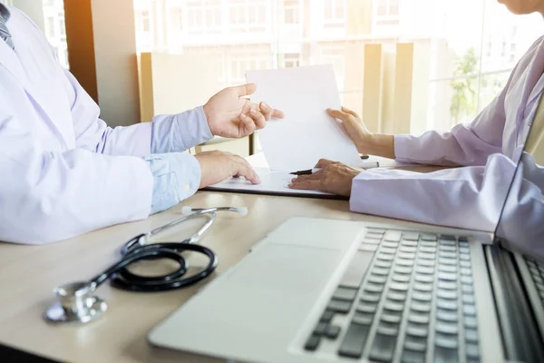 Dos doctores discutiendo notas de pacientes en un consultorio — Foto de Stock