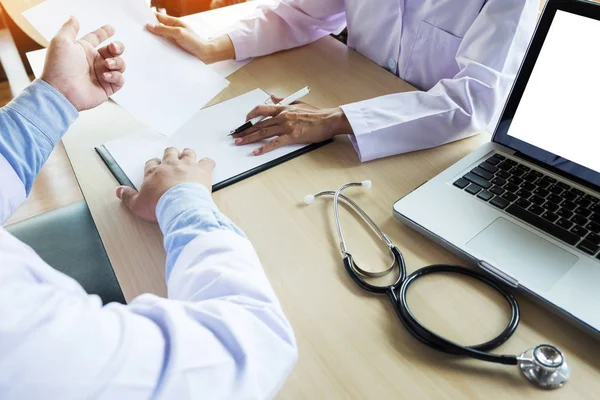 Médicos sentados à mesa e apontando para a área de transferência — Fotografia de Stock